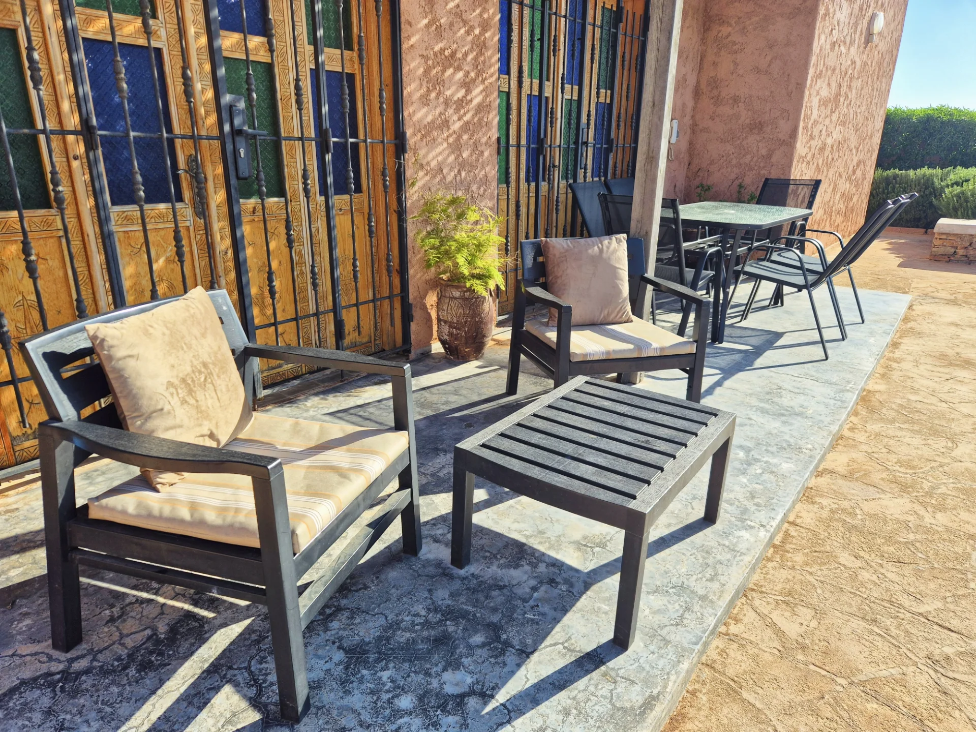 Terrasse extérieure ombragée avec table et chaises face à la piscine — Villa Dar Sara