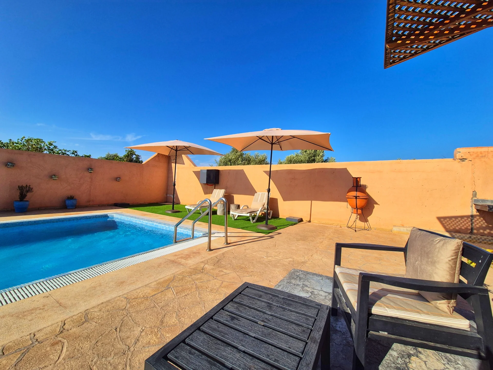 Espace lounge avec transats, parasols et douche extérieure — Villa Dar Sara