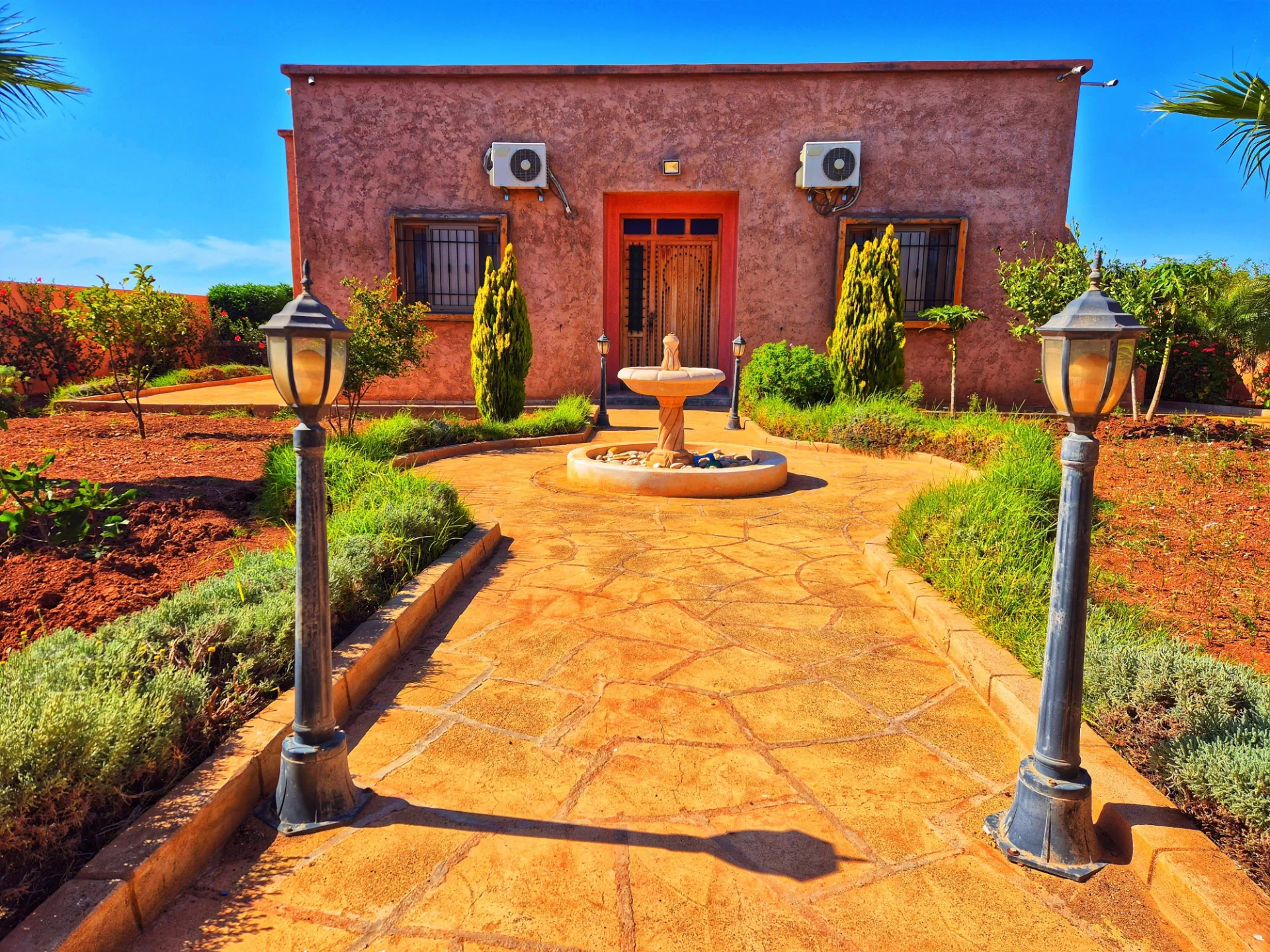 Entrée privée et sécurisée du domaine Dar Sara avec fontaine traditionnelle